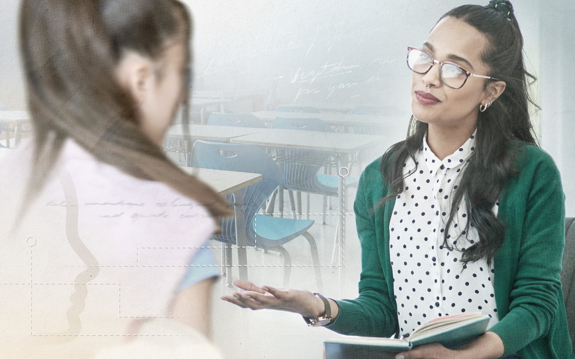 A woman with long dark hair and glasses sits in conversation with another person, who is partially visible. She is wearing a green cardigan over a white polka dot blouse and holding an open notebook. The background features classroom desks.